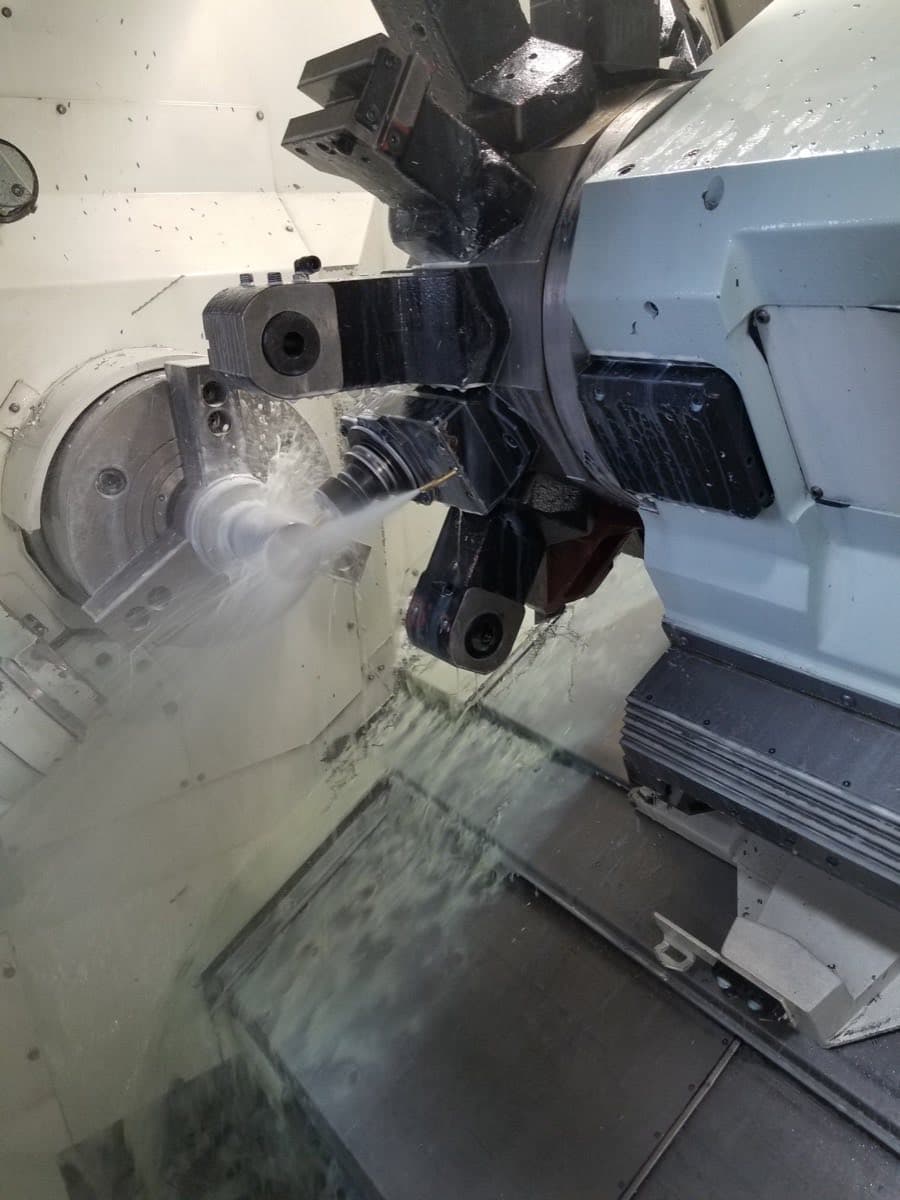 A CNC machining center cutting a precision part under coolant at Centerline Inc.